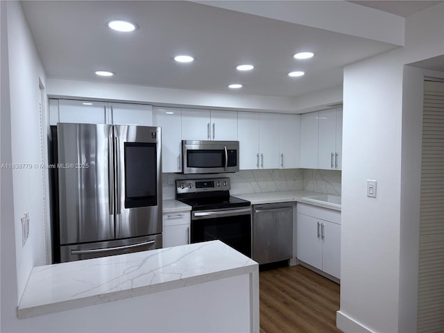 1440 Brickell Bay Dr Unit 307, Miami, FL 33131 - kitchen featuring appliances with stainless steel finishes, dark wood-style flooring, white cabinets, recessed lighting, and tasteful backsplash