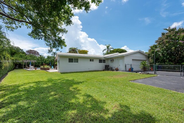 6957 SW 148th Ter, Palmetto Bay, FL 33158 - rear view of house with driveway, a garage, and a gate