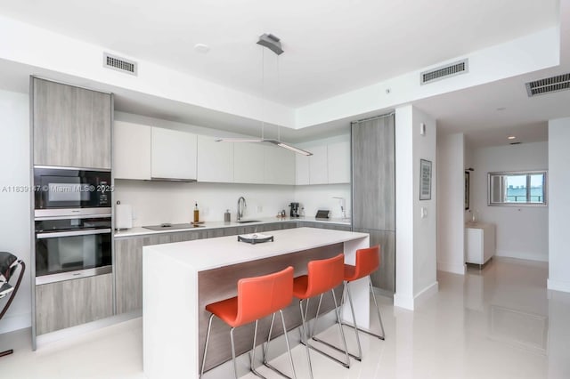 2900 NE 7th Ave Unit 404, Miami, FL 33137 - kitchen with stainless steel oven, modern cabinets, black electric cooktop, and light countertops