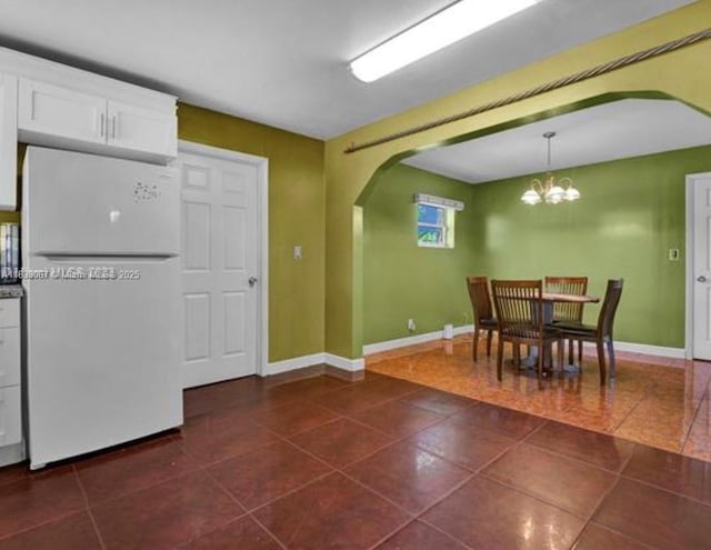 130 NE 21st Ct, Pompano Beach, FL 33060 - dining area with arched walkways, dark tile patterned flooring, and a chandelier