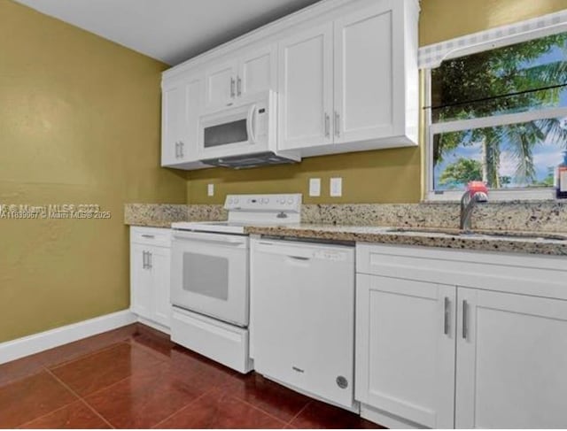 130 NE 21st Ct, Pompano Beach, FL 33060 - kitchen featuring white appliances, dark tile patterned floors, white cabinets, and light stone counters