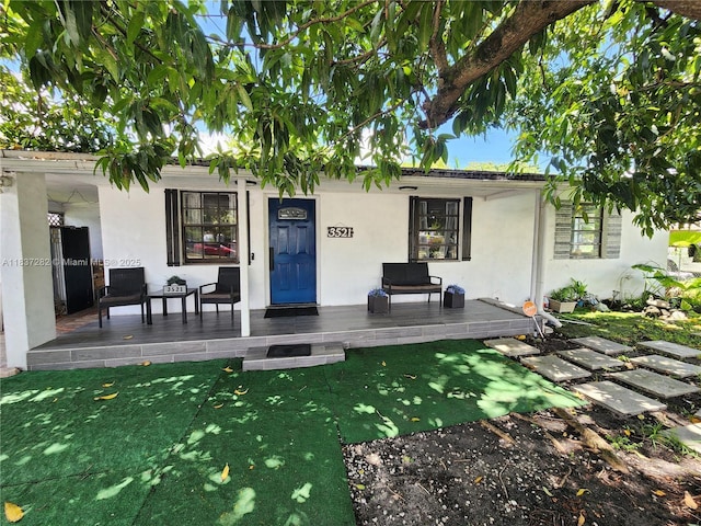 3521 E 8th Ave, Hialeah, FL 33013 - back of property with stucco siding, covered porch, and a lawn