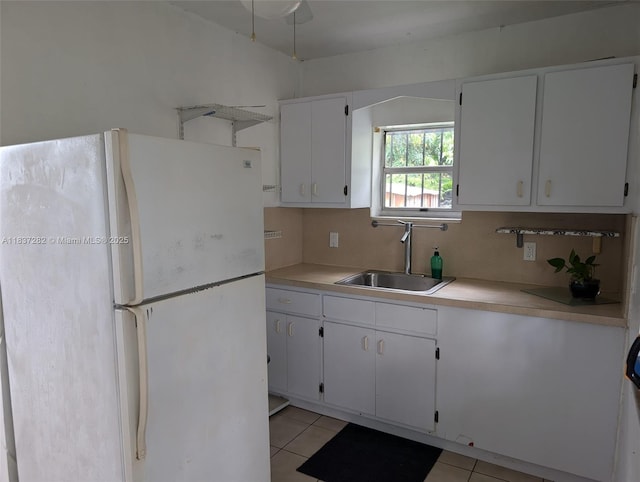 3521 E 8th Ave, Hialeah, FL 33013 - kitchen featuring freestanding refrigerator, light tile patterned flooring, light countertops, and white cabinetry