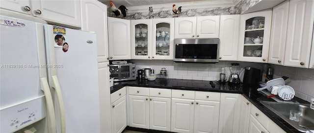 2750 NE 183rd St Unit 1701, Aventura, FL 33160 - kitchen with stainless steel microwave, freestanding refrigerator, white cabinetry, dark countertops, and decorative backsplash