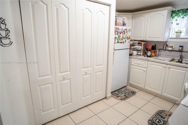 17425 NW 75th Pl Unit 101, Hialeah, FL 33015 - kitchen featuring freestanding refrigerator, white cabinets, light tile patterned flooring, and light countertops