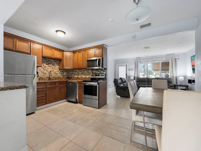 2812 SW 65th Ave, Miramar, FL 33023 - kitchen with appliances with stainless steel finishes, tasteful backsplash, light tile patterned floors, open floor plan, and brown cabinets