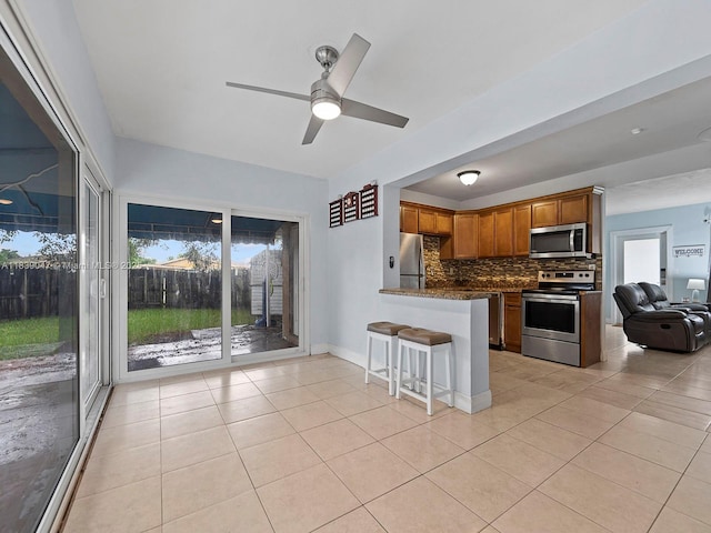 2812 SW 65th Ave, Miramar, FL 33023 - kitchen with stainless steel appliances, a peninsula, decorative backsplash, ceiling fan, and light tile patterned flooring