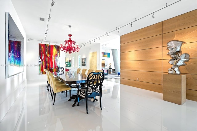 2675 S Bayshore Dr Unit 1601S, Miami, FL 33133 - tiled dining space featuring a chandelier, rail lighting, and wood walls