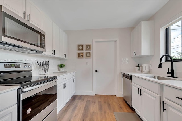 3141 SW 20th St, Fort Lauderdale, FL 33312 - kitchen featuring appliances with stainless steel finishes, light wood-type flooring, light countertops, and white cabinets