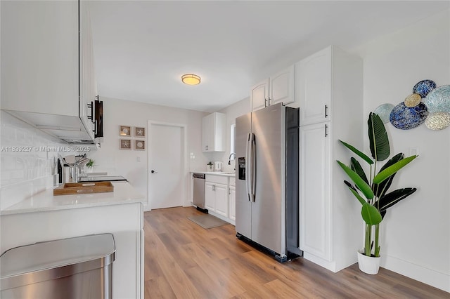 3141 SW 20th St, Fort Lauderdale, FL 33312 - kitchen featuring appliances with stainless steel finishes, light wood-style flooring, white cabinetry, and decorative backsplash