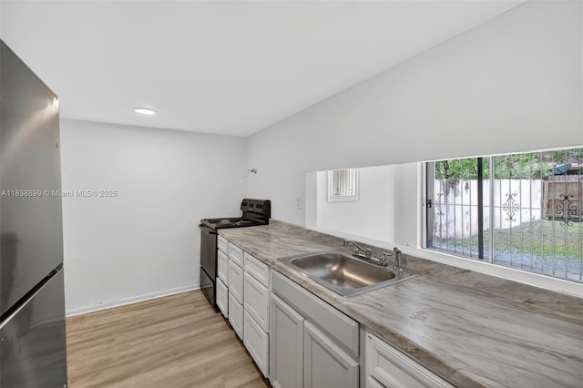 2767 NW 197th Ter, Miami Gardens, FL 33056 - kitchen with black range with electric cooktop, freestanding refrigerator, light wood-style flooring, recessed lighting, and light countertops