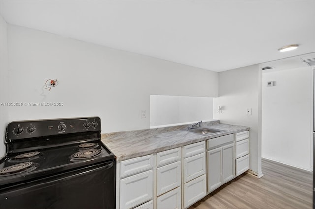 2767 NW 197th Ter, Miami Gardens, FL 33056 - kitchen with black / electric stove, light wood finished floors, and white cabinets