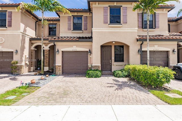 6586 S Anise Ct, Davie, FL 33314 - mediterranean / spanish-style house featuring a tile roof, an attached garage, stone siding, stucco siding, and decorative driveway