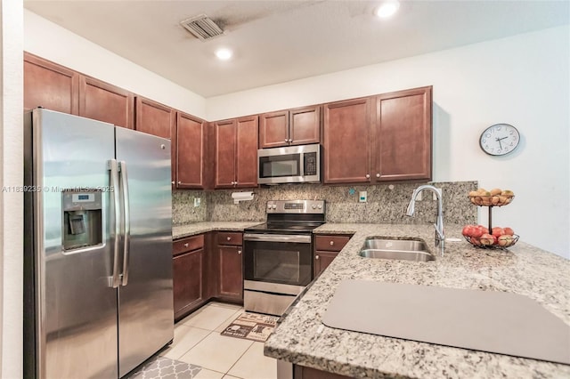6586 S Anise Ct, Davie, FL 33314 - kitchen featuring appliances with stainless steel finishes, tasteful backsplash, light stone counters, light tile patterned floors, and recessed lighting