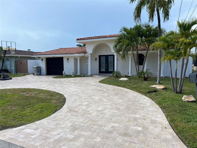 2321 SE 15th St, Pompano Beach, FL 33062 - mediterranean / spanish-style home with french doors, curved driveway, a garage, stucco siding, and a tile roof