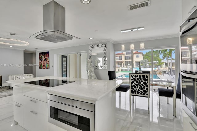 2321 SE 15th St, Pompano Beach, FL 33062 - kitchen with black electric cooktop, island range hood, stainless steel microwave, a center island, and crown molding