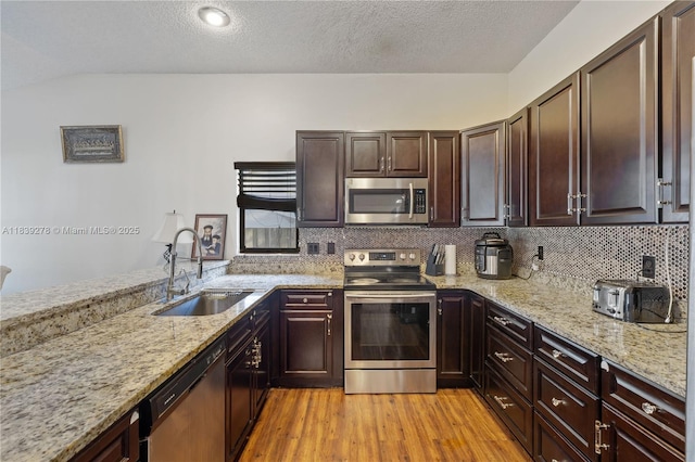 5506 Redhawk Dr, New Port Richey, FL 34655 - kitchen featuring appliances with stainless steel finishes, light wood-type flooring, light stone countertops, backsplash, and dark brown cabinets