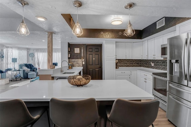 2239 NW 65th Ave, Margate, FL 33063 - kitchen with appliances with stainless steel finishes, light countertops, light wood-style floors, white cabinetry, and open floor plan