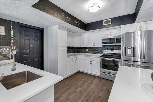 2239 NW 65th Ave, Margate, FL 33063 - kitchen featuring stainless steel appliances, light countertops, white cabinetry, tasteful backsplash, and dark wood-style flooring