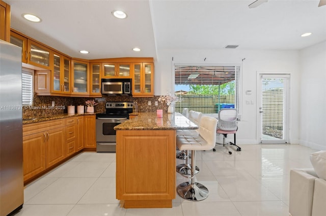 590 SW 62nd Ave, Miami, FL 33144 - kitchen with appliances with stainless steel finishes, a breakfast bar area, backsplash, dark stone countertops, and recessed lighting