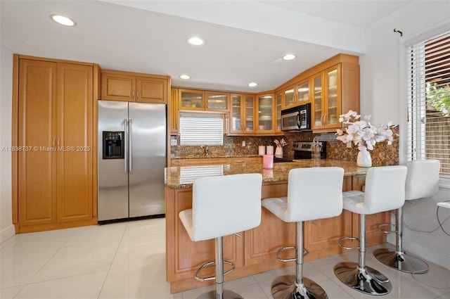 590 SW 62nd Ave, Miami, FL 33144 - kitchen with appliances with stainless steel finishes, light stone counters, a peninsula, a kitchen bar, and recessed lighting