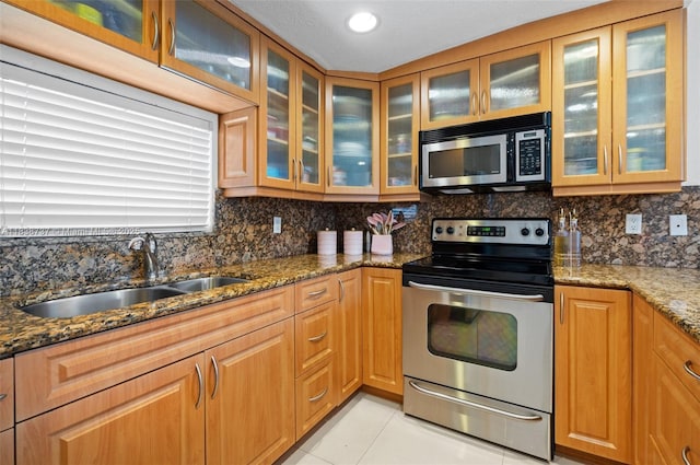 590 SW 62nd Ave, Miami, FL 33144 - kitchen featuring stainless steel appliances, dark stone countertops, backsplash, light tile patterned floors, and glass insert cabinets