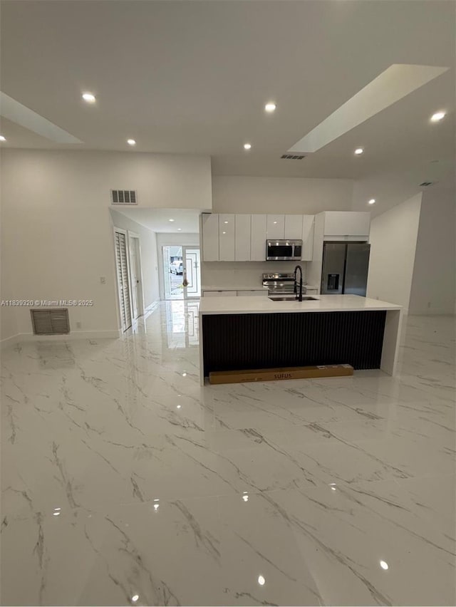 1655 NW 111th Way, Coral Springs, FL 33071 - kitchen with stainless steel appliances, modern cabinets, white cabinets, light countertops, and an island with sink