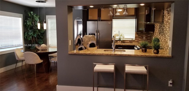 1337 Euclid Ave Unit 101, Miami Beach, FL 33139 - kitchen with stainless steel refrigerator with ice dispenser, backsplash, a peninsula, wood finished floors, and light stone countertops