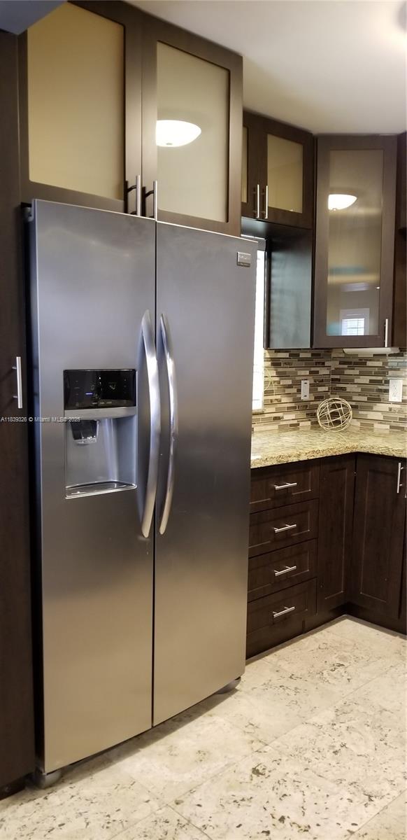 1337 Euclid Ave Unit 101, Miami Beach, FL 33139 - kitchen with stainless steel fridge with ice dispenser, dark brown cabinets, tasteful backsplash, and glass insert cabinets