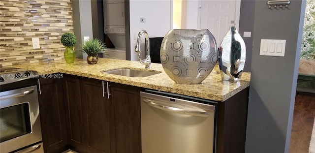 1337 Euclid Ave Unit 101, Miami Beach, FL 33139 - kitchen with stainless steel appliances, stacked washer / dryer, dark brown cabinetry, tasteful backsplash, and light stone counters