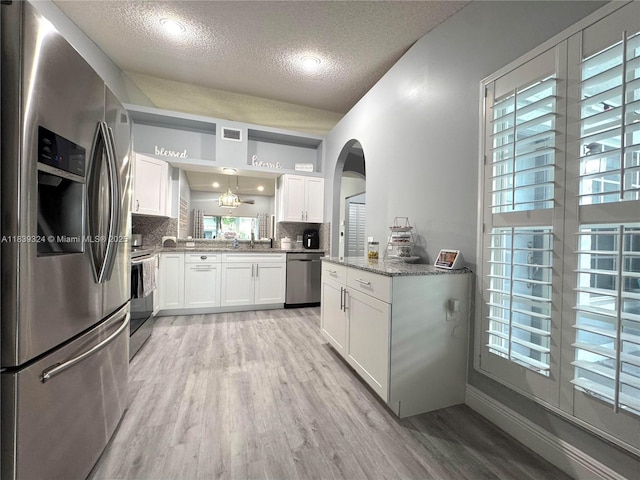 5928 NW 93rd Ter, Tamarac, FL 33321 - kitchen with stainless steel appliances, a textured ceiling, light wood-style floors, white cabinetry, and healthy amount of natural light
