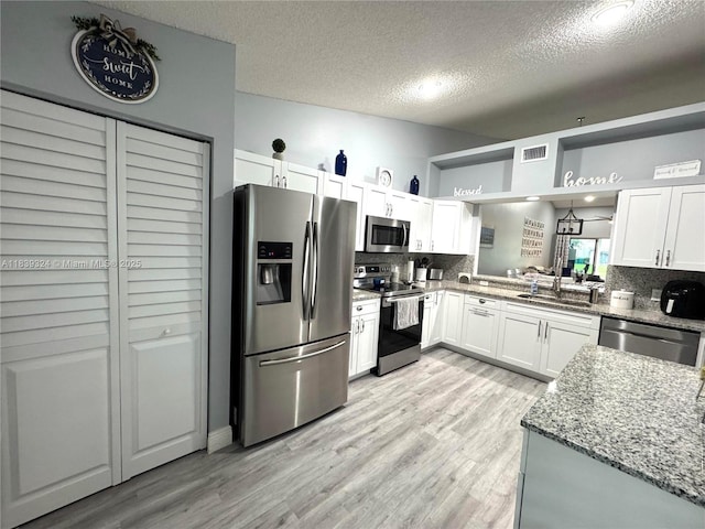 5928 NW 93rd Ter, Tamarac, FL 33321 - kitchen with appliances with stainless steel finishes, decorative backsplash, a textured ceiling, light stone countertops, and white cabinets