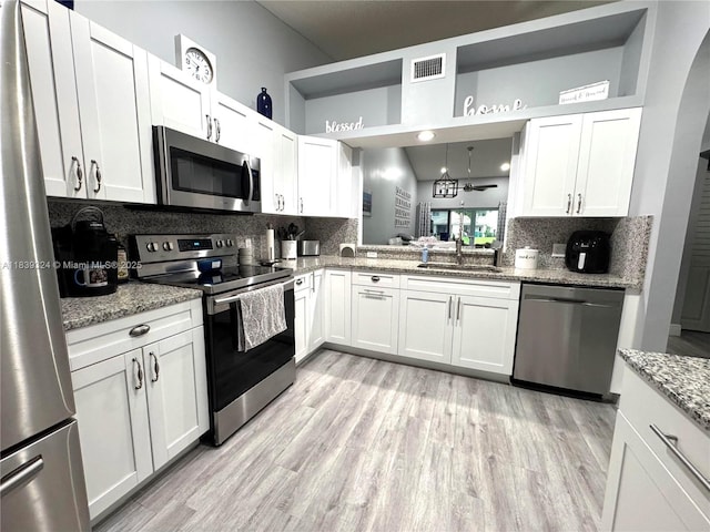 5928 NW 93rd Ter, Tamarac, FL 33321 - kitchen with appliances with stainless steel finishes, decorative backsplash, light wood-style floors, and white cabinets