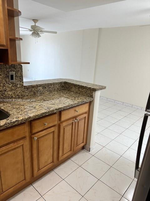 720 Collins Ave Unit 310, Miami Beach, FL 33139 - kitchen with open shelves, brown cabinetry, a ceiling fan, dark stone countertops, and a peninsula