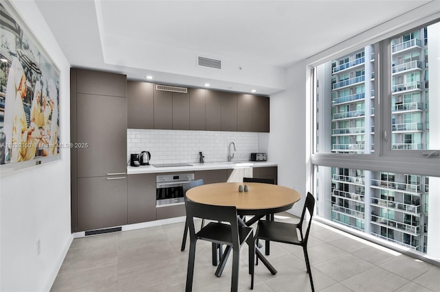 227 NE 2nd St Unit 2000, Miami, FL 33132 - kitchen featuring oven, modern cabinets, tasteful backsplash, light countertops, and light tile patterned floors