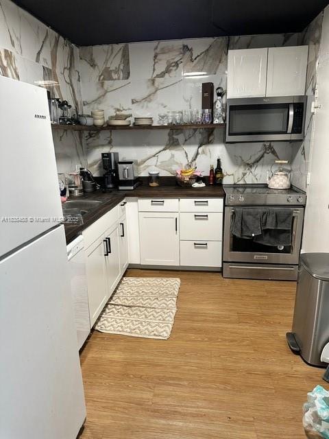 400 S Kings Point Dr Unit 806, Sunny Isles Beach, FL 33160 - kitchen with appliances with stainless steel finishes, dark countertops, white cabinets, and light wood finished floors