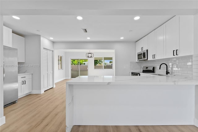 7021 SW 12th St, Pembroke Pines, FL 33023 - kitchen featuring appliances with stainless steel finishes, backsplash, light wood-type flooring, a peninsula, and recessed lighting