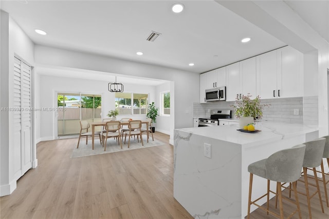 7021 SW 12th St, Pembroke Pines, FL 33023 - kitchen featuring appliances with stainless steel finishes, decorative backsplash, white cabinets, recessed lighting, and plenty of natural light