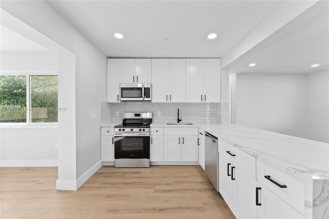 7021 SW 12th St, Pembroke Pines, FL 33023 - kitchen with stainless steel appliances, light stone counters, decorative backsplash, white cabinets, and light wood-style flooring