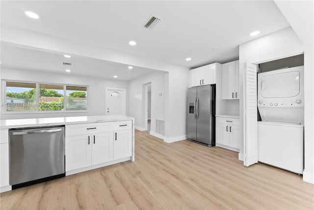 7021 SW 12th St, Pembroke Pines, FL 33023 - kitchen with stainless steel appliances, stacked washing machine and dryer, white cabinets, light wood-type flooring, and recessed lighting