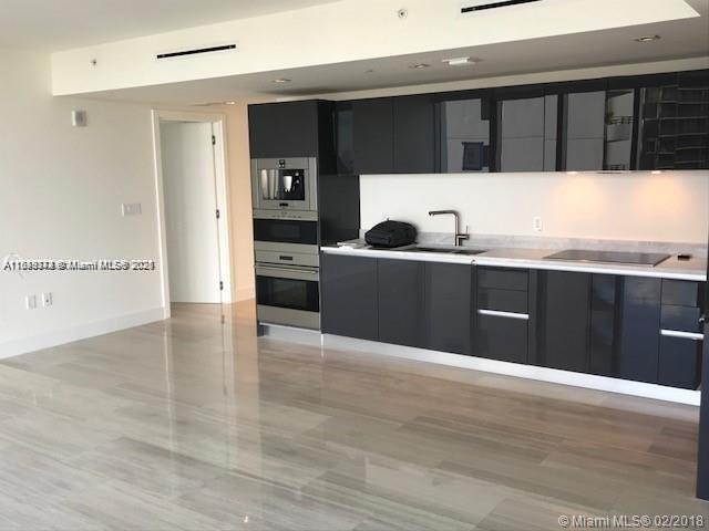 1451 Brickell Ave Unit 902, Miami, FL 33131 - kitchen with modern cabinets, black electric stovetop, dark cabinets, and light countertops