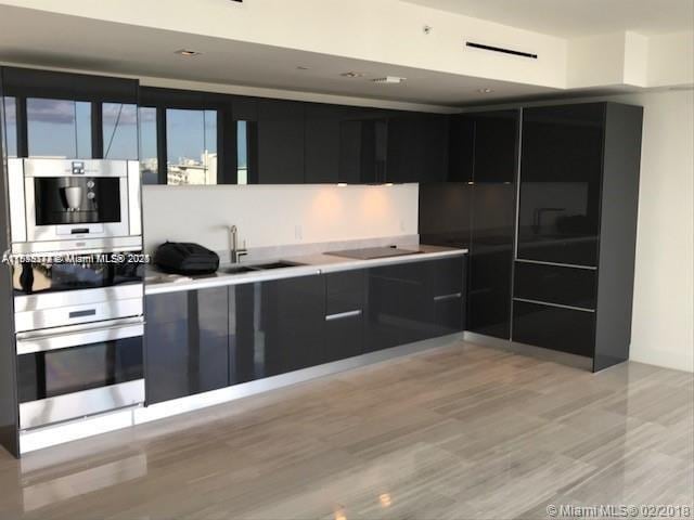 1451 Brickell Ave Unit 902, Miami, FL 33131 - kitchen featuring oven, modern cabinets, dark cabinetry, black electric cooktop, and light countertops
