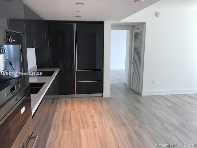 1451 Brickell Ave Unit 902, Miami, FL 33131 - kitchen featuring modern cabinets, dark cabinets, light wood finished floors, light countertops, and black electric stovetop