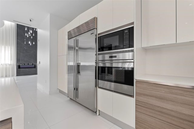 10431 NW 68th Ter, Doral, FL 33178 - kitchen featuring built in appliances, white cabinets, modern cabinets, light tile patterned flooring, and light countertops