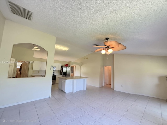 5338 NW S Crisona Cir, Port St Lucie, FL 34986 - unfurnished living room with ceiling fan, lofted ceiling, arched walkways, light tile patterned flooring, and a textured ceiling
