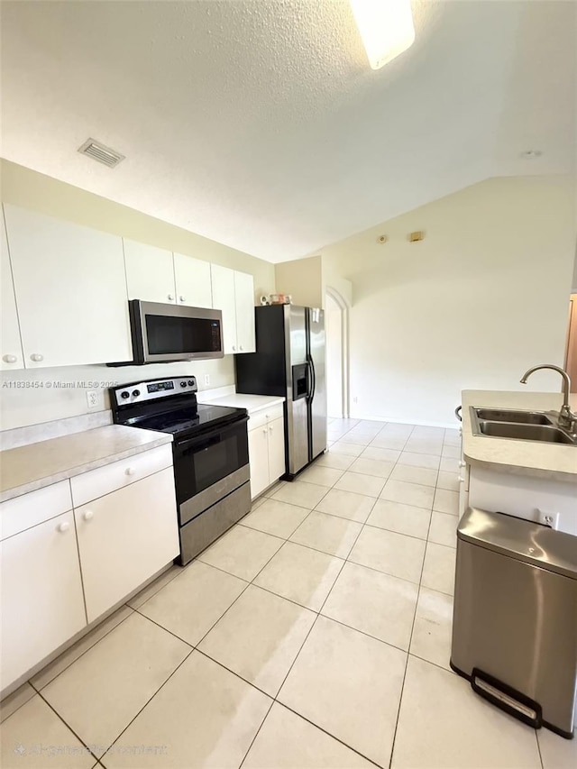 5338 NW S Crisona Cir, Port St Lucie, FL 34986 - kitchen with appliances with stainless steel finishes, white cabinetry, light countertops, light tile patterned flooring, and vaulted ceiling
