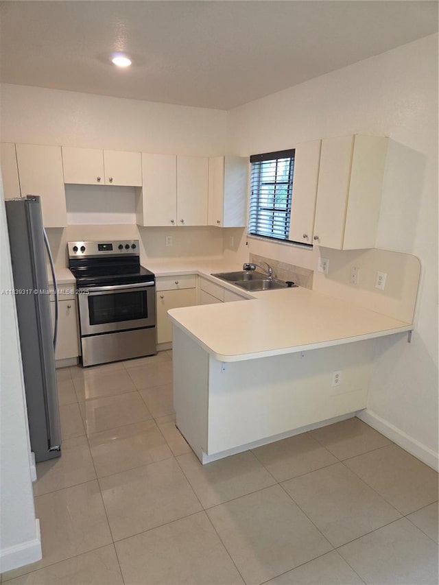2630 NE 3rd Dr Unit 101, Homestead, FL 33033 - kitchen with stainless steel appliances, a peninsula, light countertops, light tile patterned flooring, and white cabinets