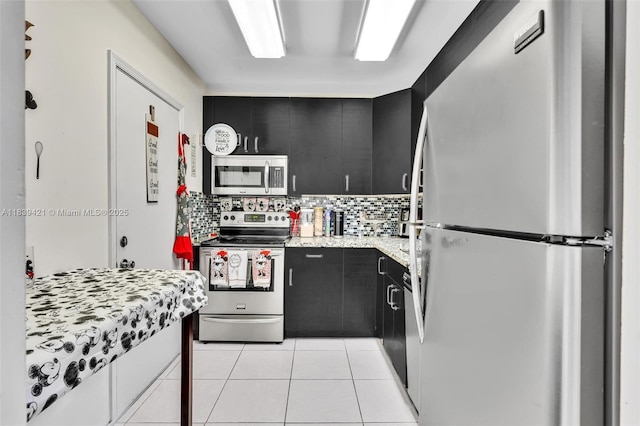 5800 NE 22nd Way Unit 523, Fort Lauderdale, FL 33308 - kitchen with stainless steel appliances, dark cabinets, light tile patterned flooring, and decorative backsplash