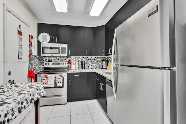 5800 NE 22nd Way Unit 523, Fort Lauderdale, FL 33308 - kitchen with stainless steel appliances, dark cabinetry, light tile patterned floors, and decorative backsplash