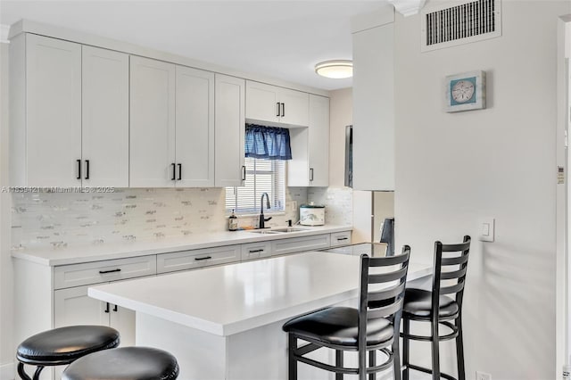 5800 NE 22nd Way Unit 523, Fort Lauderdale, FL 33308 - kitchen featuring a breakfast bar area, decorative backsplash, light countertops, and white cabinets